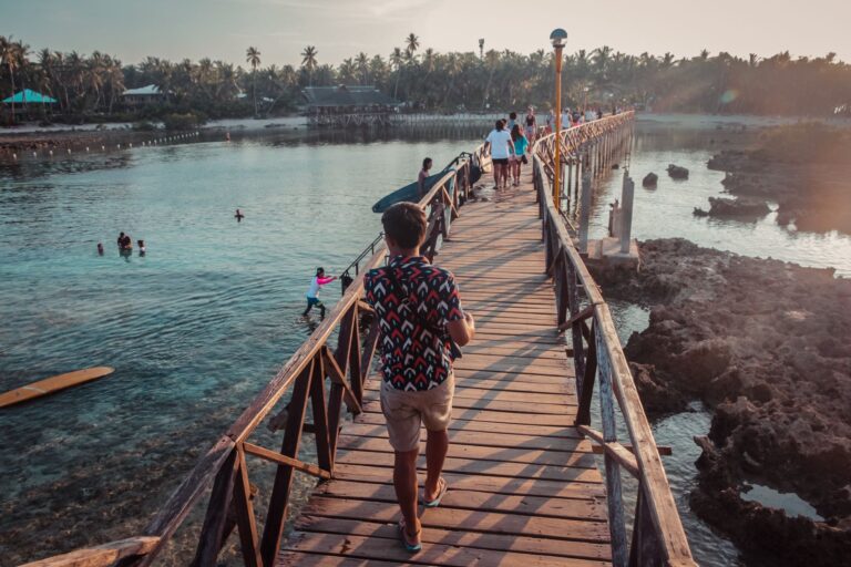 Travellers and residents crossing a wooden bridge in General Luna, Siargao, where the World Mobile Frontier AirNode rollout begins